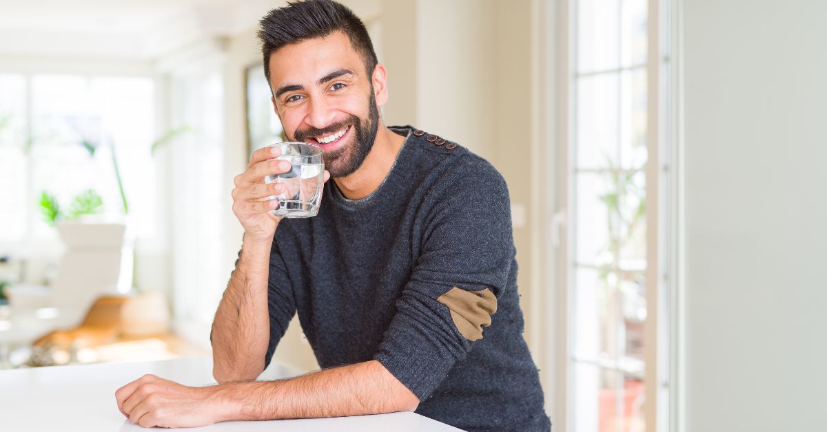 man holding glass of clear water