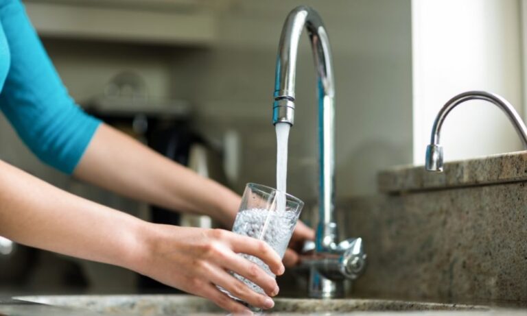 woman filling water glass by sink